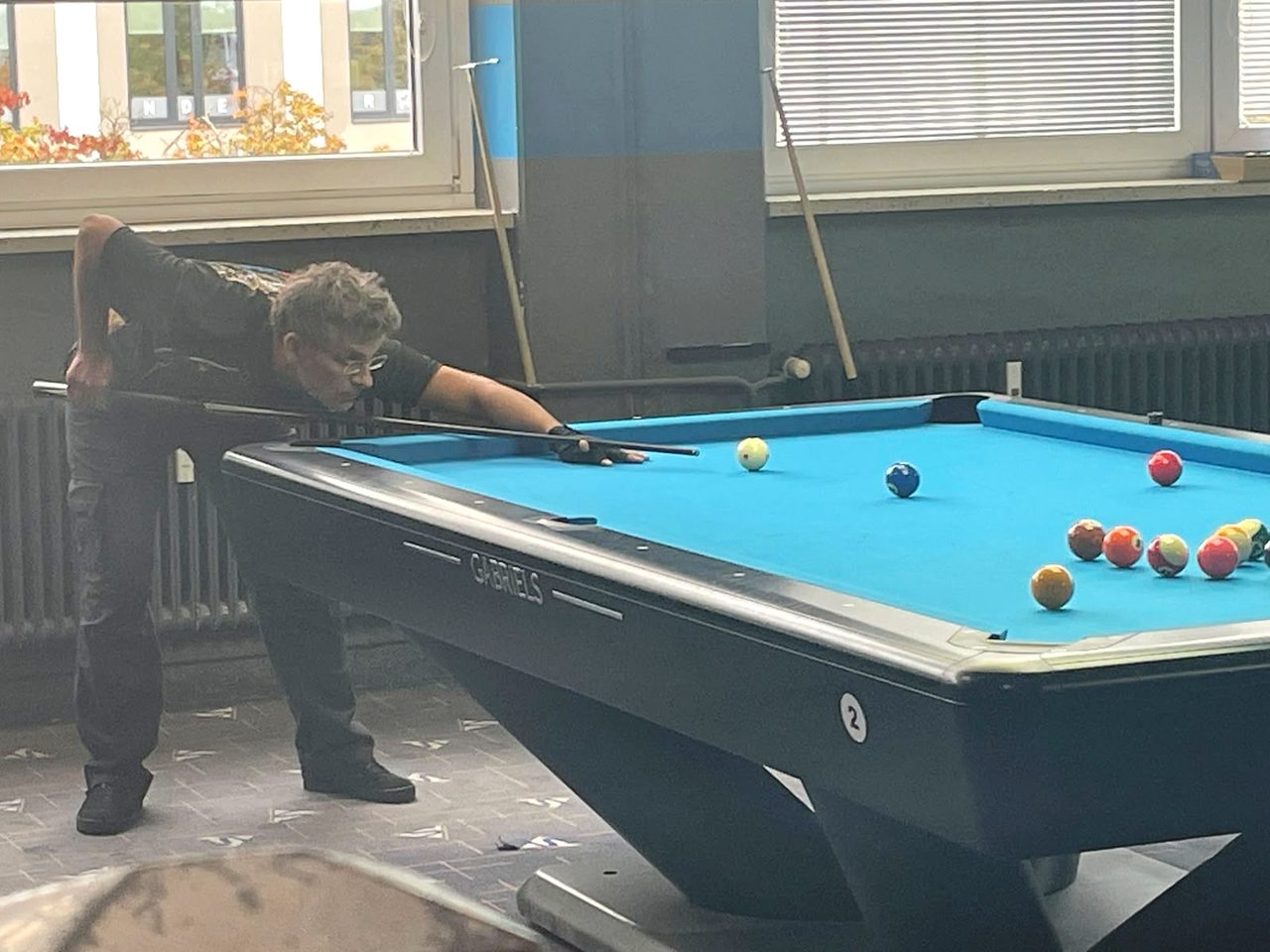 Spieler der 5. Mannschaft beim Anspielen an einem Billardtisch mit blauem Tuch