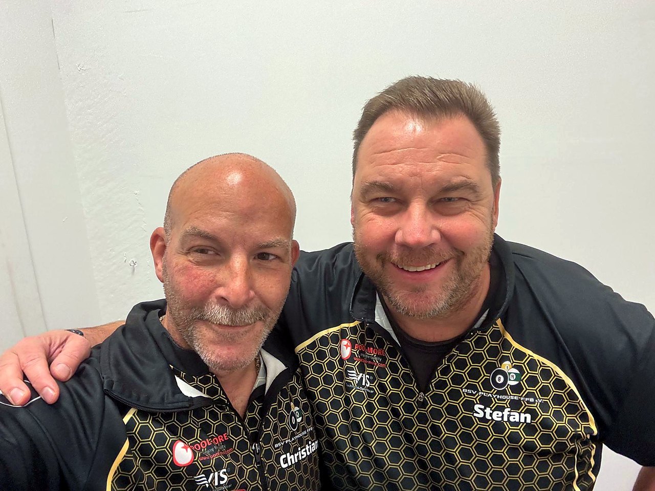Zwei lächelnde Männer in schwarz-goldenen Vereinstrikots des BSV Playhouse FFB machen ein Selfie, links Christian, rechts Stefan